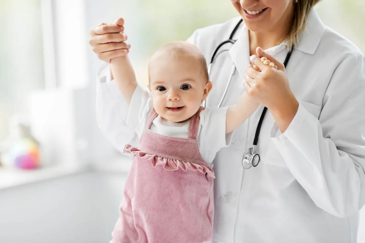 baby in pink held by smiling doctor